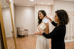 Consultora compara tecidos branco puro e marfim durante prova de vestido de noiva