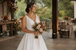 Noiva com vestido off-white segura buquê em tons creme, rosa queimado e terracota